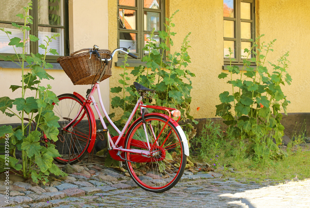 Red women's bicycle with a basket. Bike are parked in a bicycle rack.