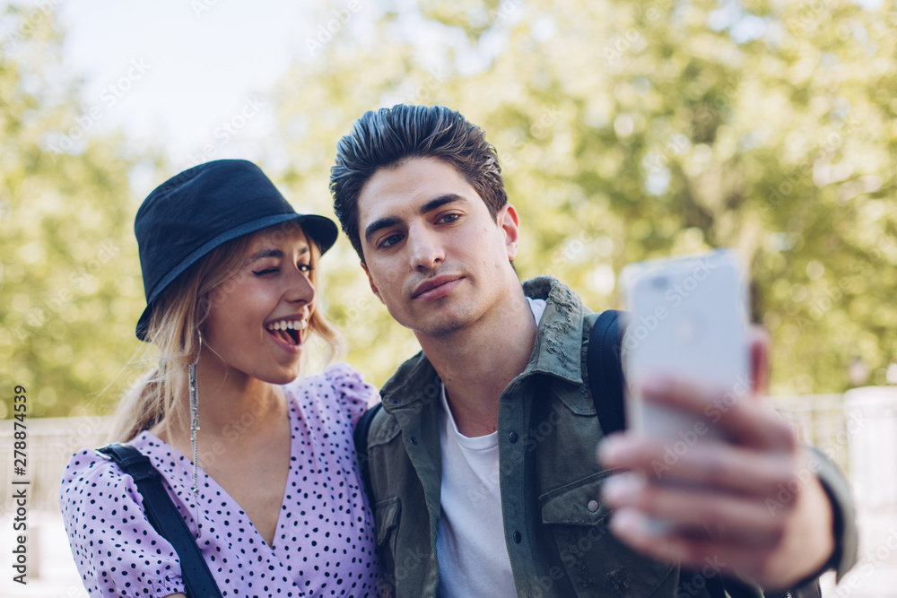 Young couple taking selfie with smartphone in garden Young couple taking selfie with smartphone in garden
