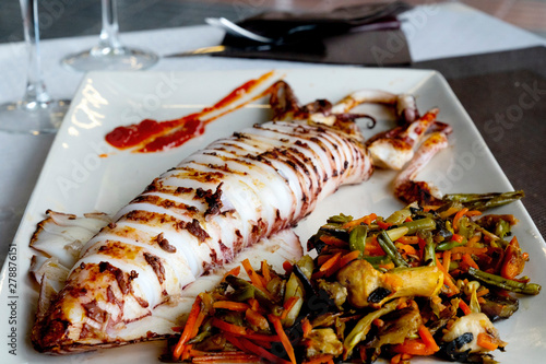 Grilled big squid - typical Spanish tapas. Gourmet dinner in the sea food restaurant in Algeciras. Southern Spain is a paradise for sea food lovers.