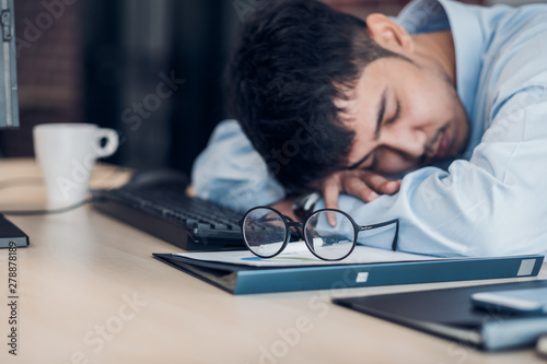 Tired asian businessman sleep on working desk table in office.working hard and late.burn out syndrome.