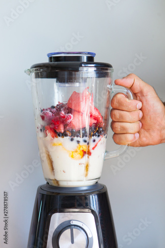 A blender filled with fresh whole fruits for making a smoothie or juice. Healthy eating concept.