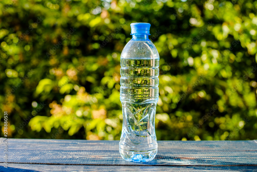 A bottle of drinking water stands on a green natural background A bottle of drinking water stands on a green natural background