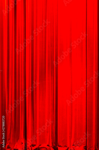 Front view of a closed vintage style red velvet theater curtain illuminated by a spotlight
