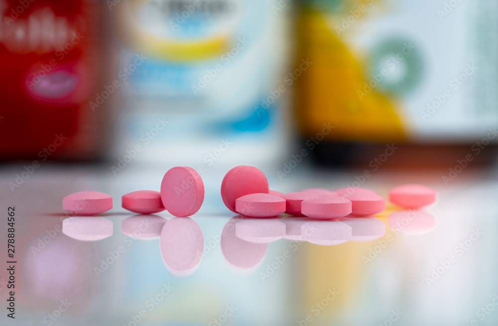 Pink tablets pills on blurred background of drug box and drug bottle ...
