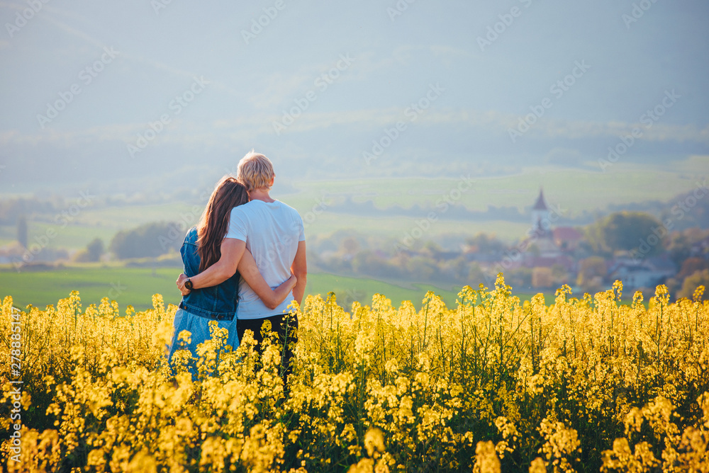 Couple in love standing in yellow spring nature. Romantic photo, man and woman, white edit space