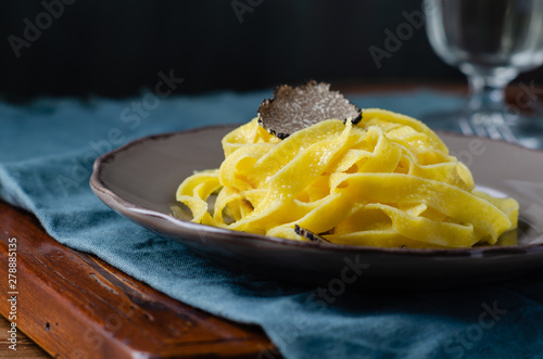 Italian cuisine- tagliatelle with black truffle on rustic plate.
