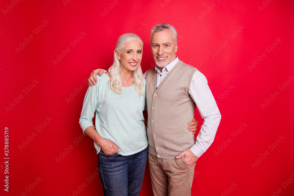 Close up photo funny amazing beautiful she her he him his old guy lady standing hugging sincere beaming smile easy-going best partners wear sweater pullover shirt waistcoat isolated red background