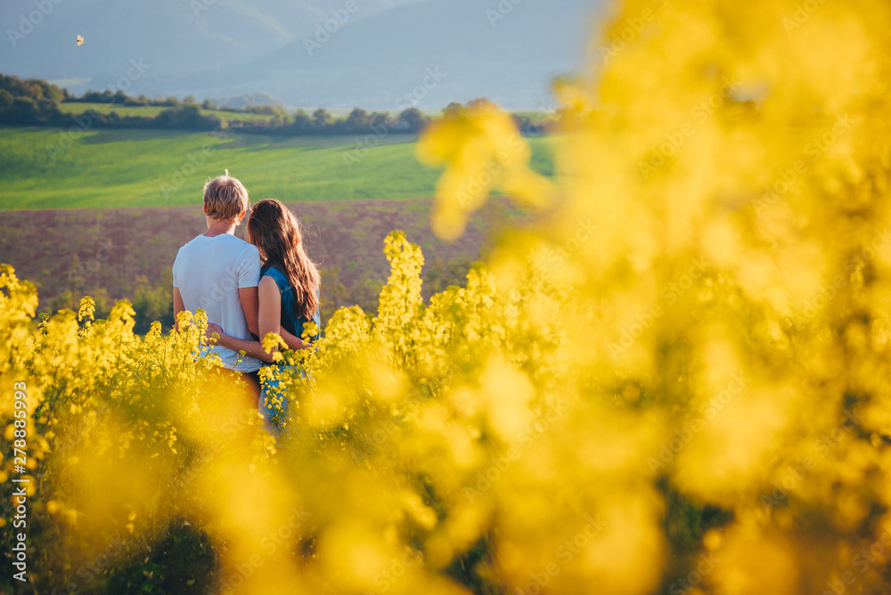 Young couple together outside in spring canola field Young couple together outside in spring canola field