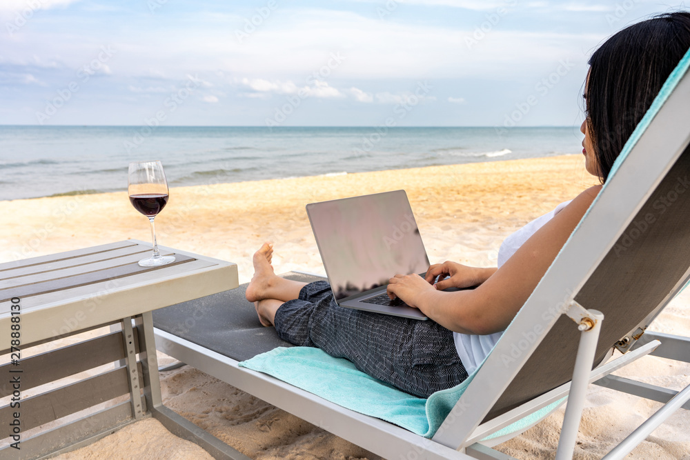 Woman using laptop on the beautiful beach
