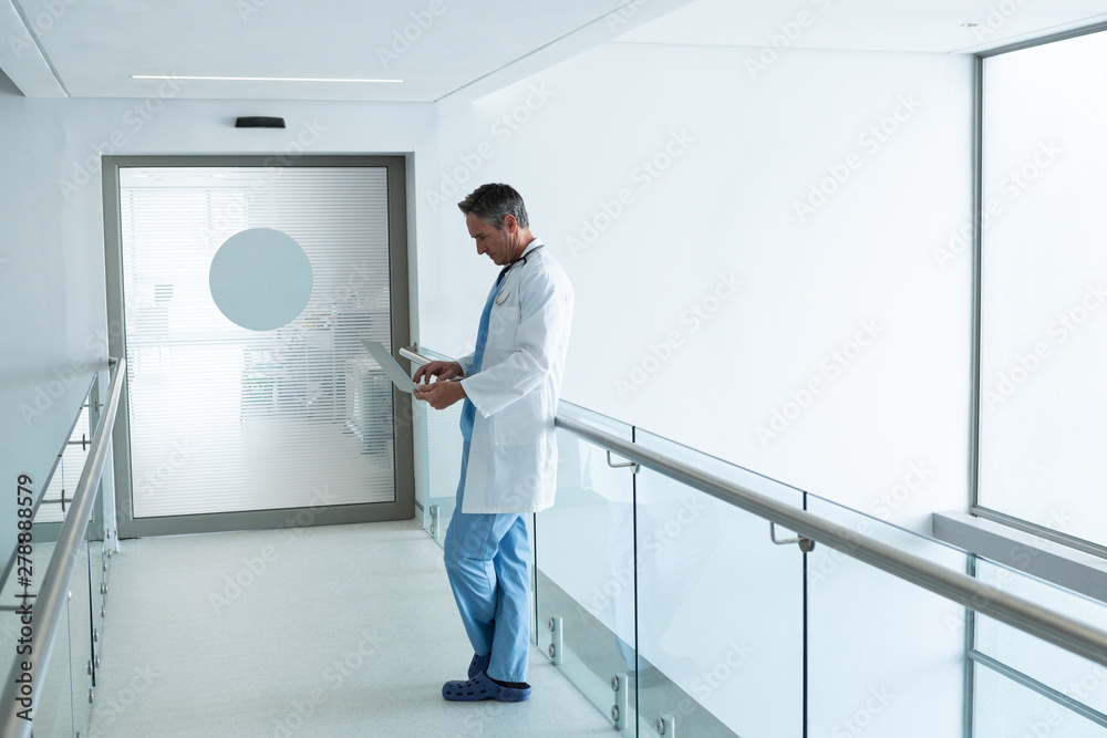 Male doctor using laptop in the corridor in hospital