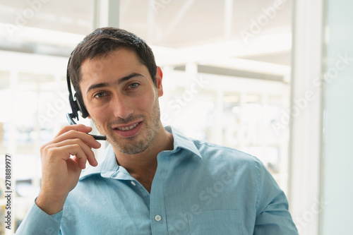 Male customer service executive talking on headset at desk