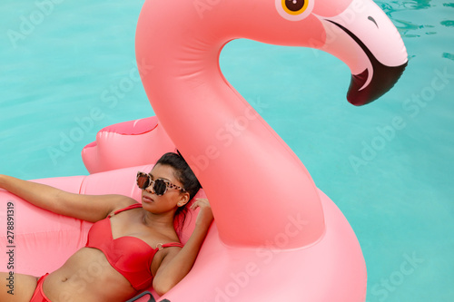 Woman in bikini relaxing on a inflatable tube in swimming pool at the backyard of home © wavebreak3