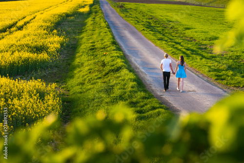 Beauty family man and woman walk and see to yellow canola field in summer © kovop58