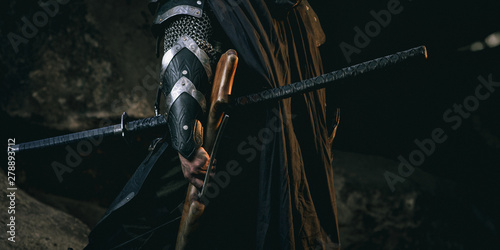 Foto Mystery scarface knight in armor with sword and crossbow in the forest