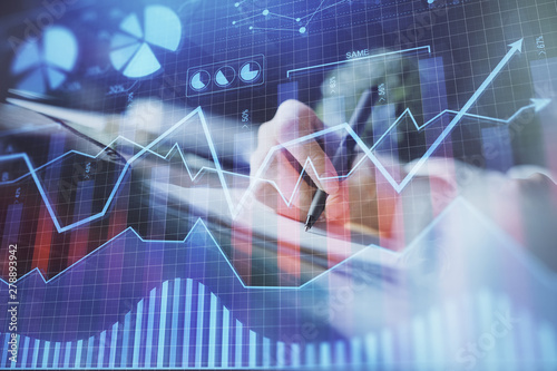 Financial forex graph displayed on hands taking notes background. Concept of research. Multi exposure