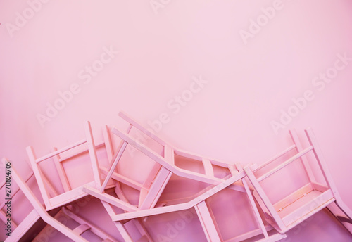 Many pink chairs upside down against the background of a pink wall