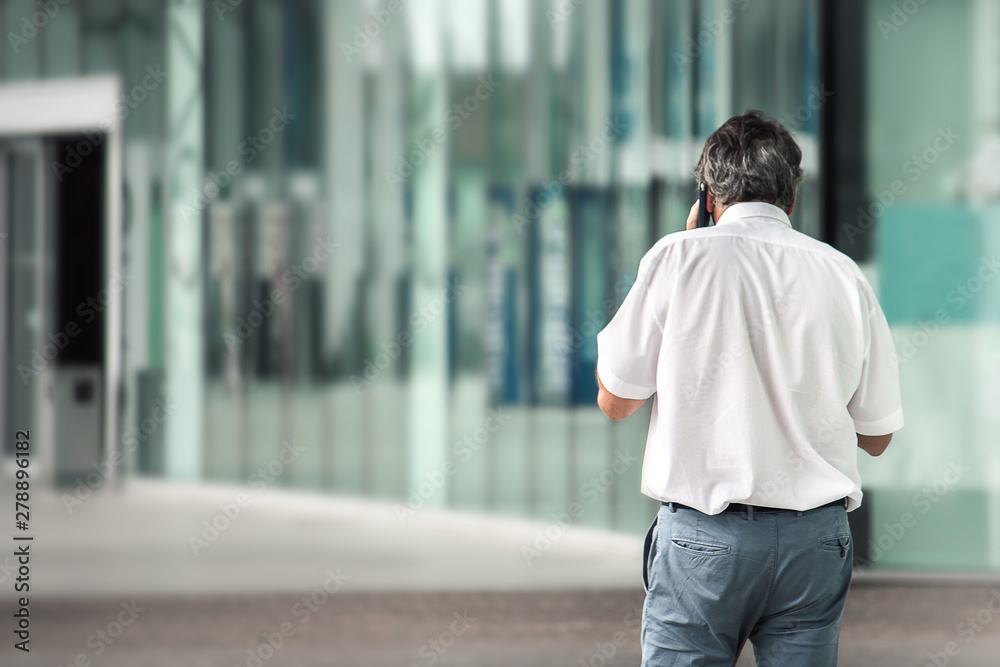 back view of elegant man talking on phone, defocused background for text