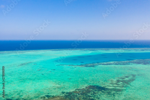 Atoll and blue sea, view from above. Seascape by day. Turquoise and blue sea water.