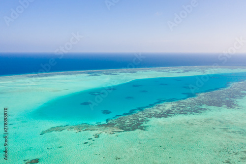 Fototapeta Naklejka Na Ścianę i Meble -  Atoll and blue sea, view from above. Seascape by day. Turquoise and blue sea water.
