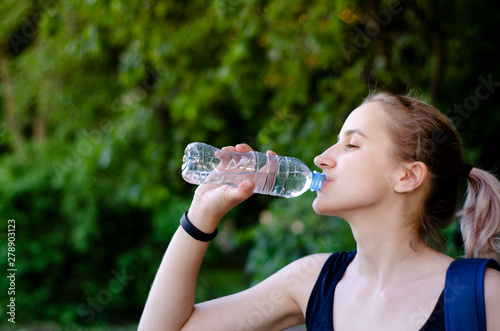 Beautiful girl drinking water after exercise. Playing sport.