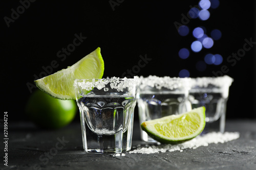 Tequila shots with salt and lime slices on black background photo