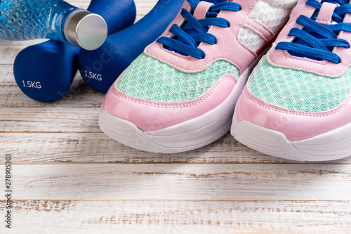 Sport shoes, dumbbells, bottle of water on wooden background. Sport equipment. Healthy lifestyle, sport and slimming concept. Copy space