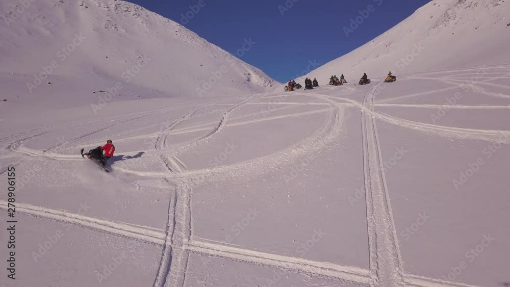 snowmobile driver makes circle trace on white bright smooth snow surface of wide valley surrounded by beautiful hills snowmobile driver makes circle trace on white bright smooth snow surface of wide valley surrounded by beautiful hills