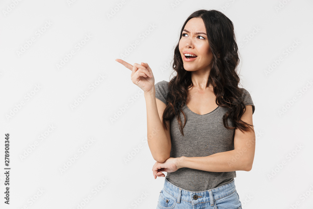 Image of caucasian brunette woman 20s dressed in basic clothes smiling and pointing finger at copyspace Image of caucasian brunette woman 20s dressed in basic clothes smiling and pointing finger at copyspace