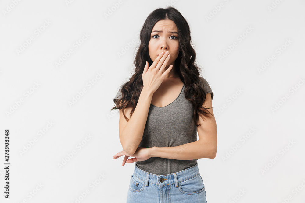 Image of displeased brunette woman 20s dressed in basic clothes worrying and covering mouth Image of displeased brunette woman 20s dressed in basic clothes worrying and covering mouth