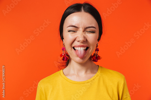 Excited happy young woman posing isolated over orange wall background.