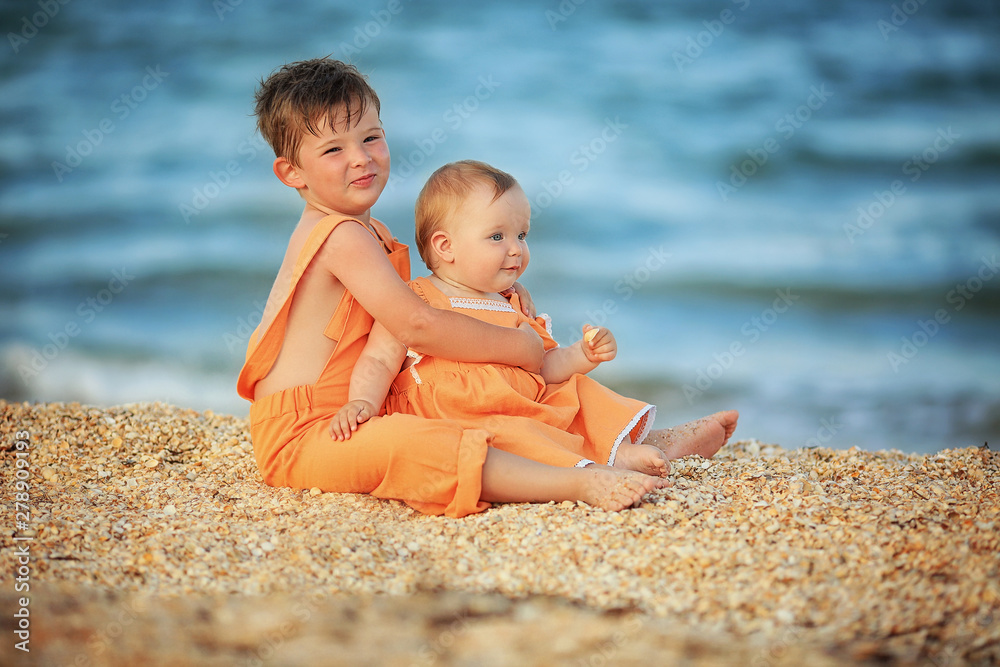 boy and girl near the sea in the same orange clothes boy and girl near the sea in the same orange clothes