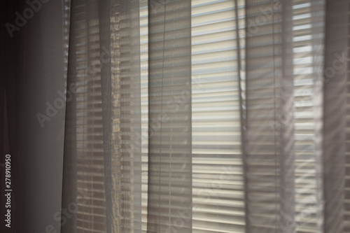Gray transparen curtains at wide jalousie window.