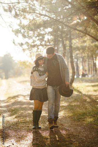Lovely hipster couple enjoying each other. Couple wearing beautiful hats and sweaters. Lifestyle, happy couple of two play on a sunny day in the park. The concept of youth, love and lifestyle. 