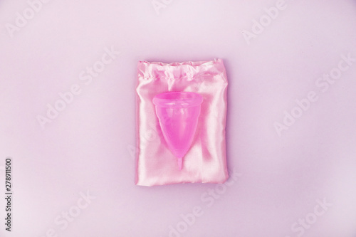 A woman holds a menstrual cup in her hand on a pink background. The concept of women's health, hygiene, alternatives pads and tampons photo