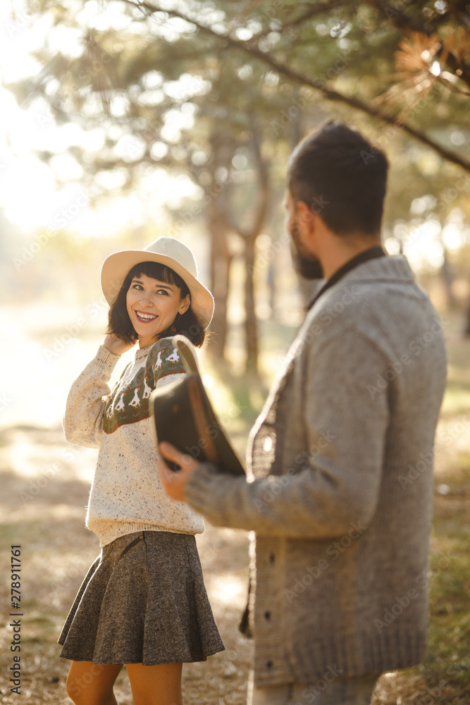 Fototapeta premium Lovely hipster couple enjoying each other. Couple wearing beautiful hats and sweaters. Lifestyle, happy couple of two play on a sunny day in the park. The concept of youth, love and lifestyle. 