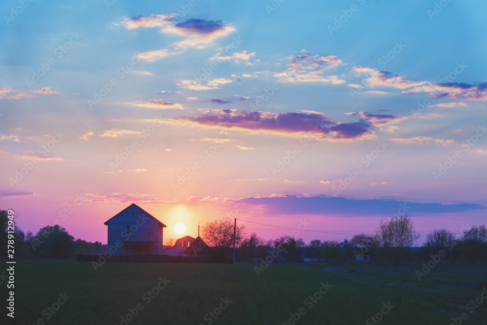 Rural landscape in the evening at sunset. Silhouette of a village against the beautiful evening sky