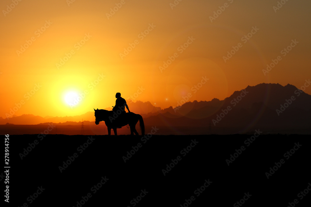 Cowboy reitet bei Sonnenuntergang auf seinem Pferd