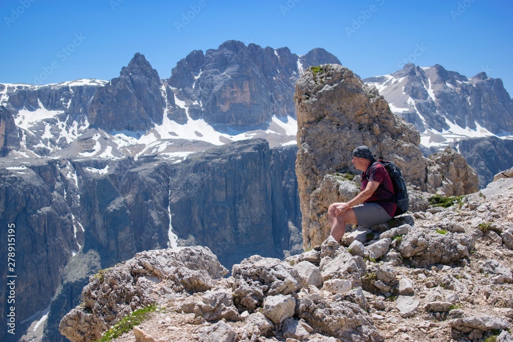 Hiker sitting on the mountain peak enjoying beautiful mountain scenery - Dolomites Italy.