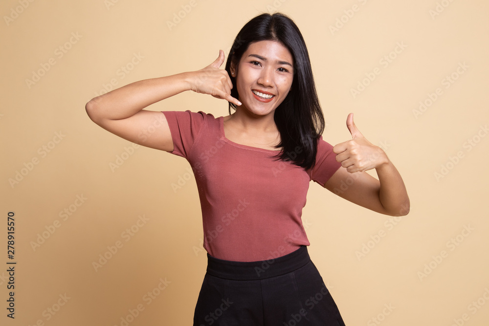 Young Asian woman thumbs up show with phone gesture. Young Asian woman thumbs up show with phone gesture.