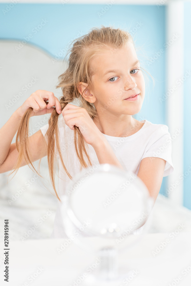 Little girl braids herself in the morning at home Little girl braids herself in the morning at home