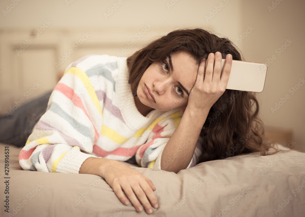 Portrait of a bored, unhappy and tired pretty young girl using m Portrait of a bored, unhappy and tired pretty young girl using m