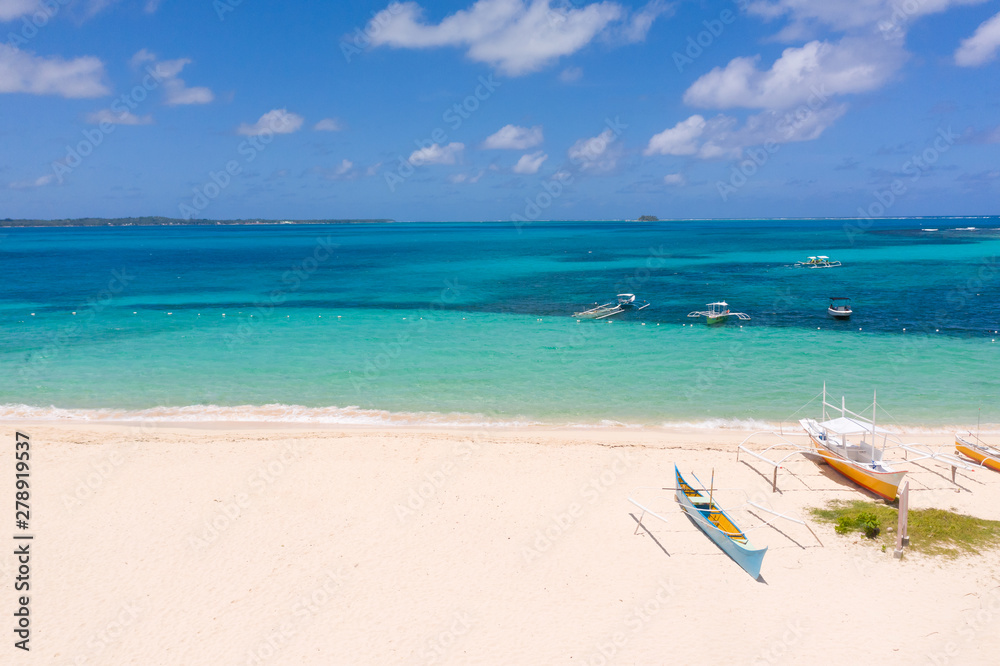White sandy beach with boats. White beach with turquoise lagoon. Seashore in sunny weather.