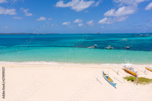 White sandy beach with boats. White beach with turquoise lagoon. Seashore in sunny weather.