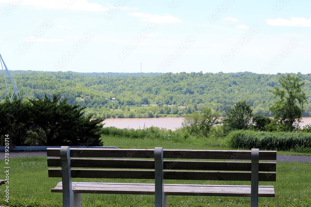 A wood park bench with a view of the river in the valley. A wood park bench with a view of the river in the valley.