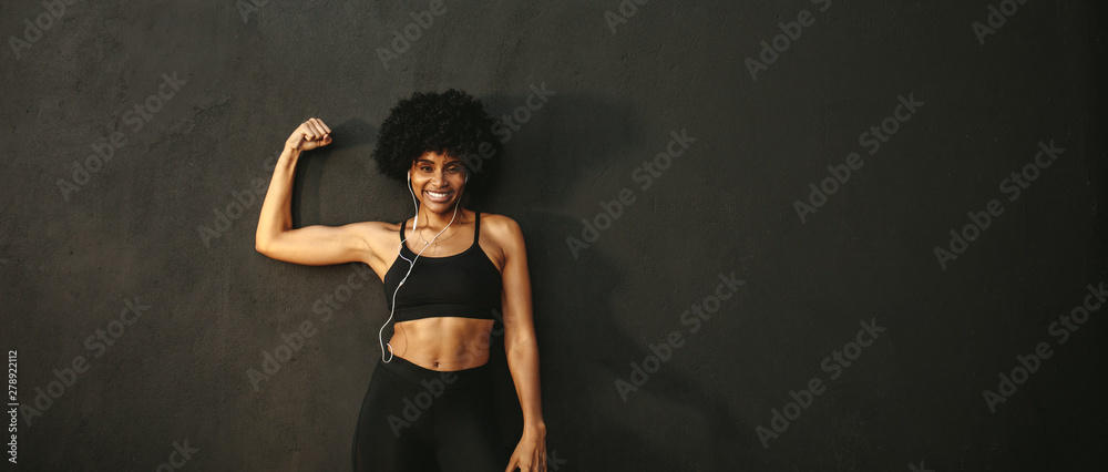 Obraz premium Fitness woman flexing muscles and smiling