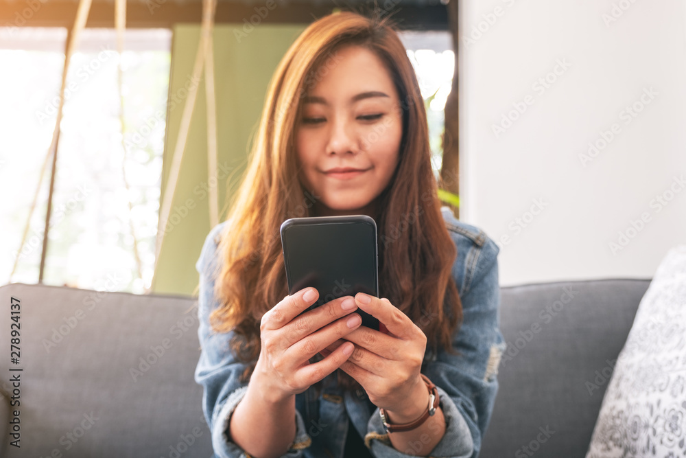 Closeup image of a beautiful asian woman holding , using and looking at smart phone Closeup image of a beautiful asian woman holding , using and looking at smart phone