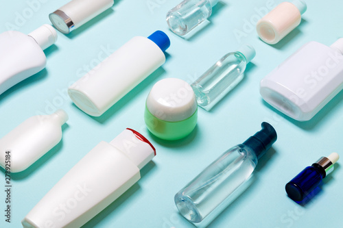 Top view of cosmetic products in different jars and bottles on blue background. Close-up of containers with copy space