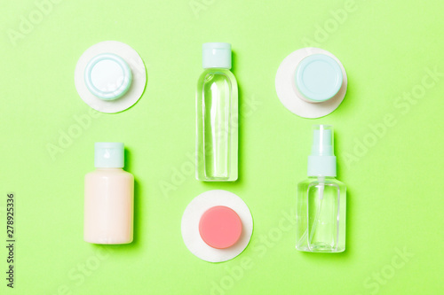 Set of travel size cosmetic bottles on green background. Flat lay of cream jars. Top view of bodycare style concept