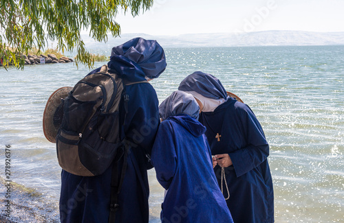 Tabgha, Israel - May 18 2019 : Nuns visiting the shore of Sea of Galilee in Tabgha church