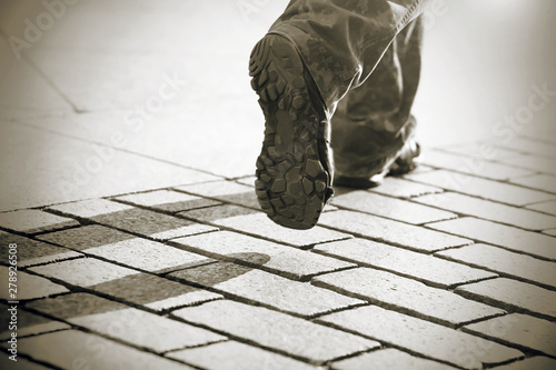 A man in military camouflage and comfortable sneakers running on the city sidewalk. The image is in black and white, which seems to convey the mood of a person going to the light. photo